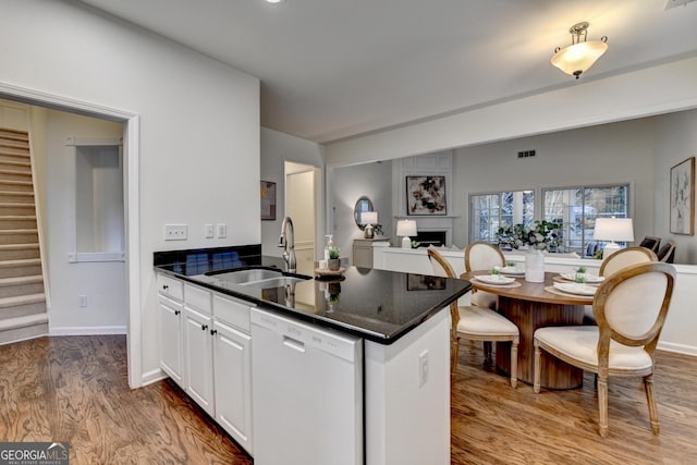 kitchen featuring white cabinets, dishwasher, open floor plan, a fireplace, and a sink