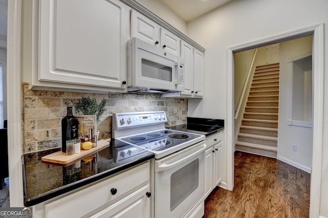 kitchen with white appliances, white cabinets, decorative backsplash, dark countertops, and dark wood-type flooring