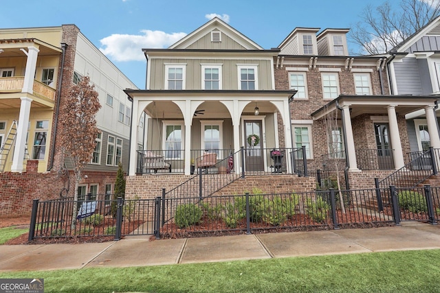 townhome / multi-family property with stairs, a porch, brick siding, and a fenced front yard