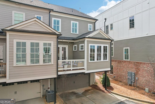 back of property with central AC, concrete driveway, and an attached garage