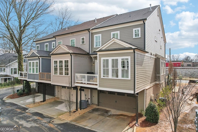 back of property with driveway, central AC, and a garage