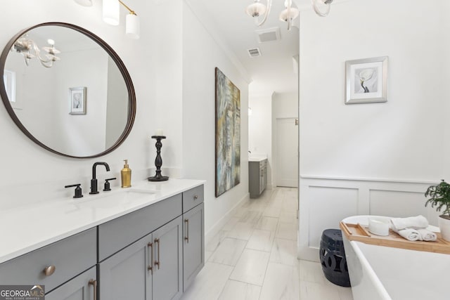 bathroom featuring vanity, a freestanding bath, visible vents, and a chandelier