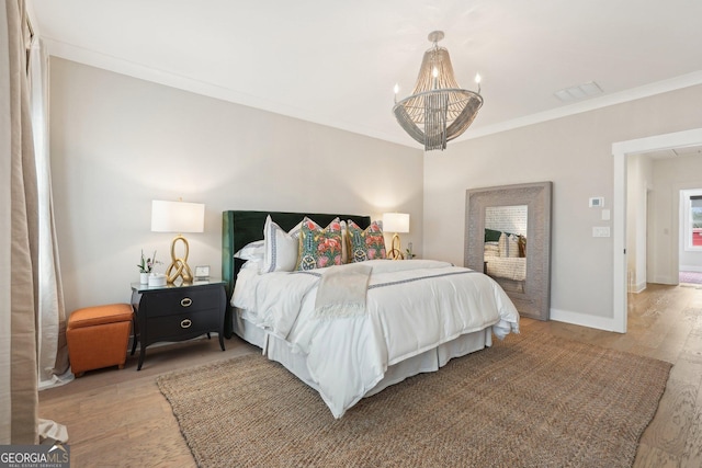 bedroom with wood finished floors, baseboards, visible vents, ornamental molding, and a notable chandelier