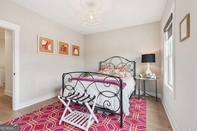 bedroom featuring multiple windows, baseboards, and wood finished floors