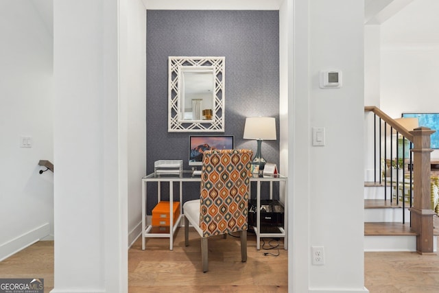home office with baseboards, wood finished floors, an accent wall, and wallpapered walls