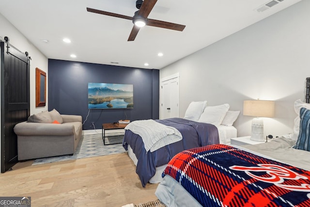 bedroom featuring visible vents, a ceiling fan, recessed lighting, a barn door, and light wood-style floors
