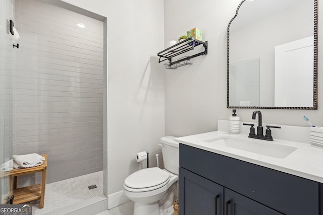 bathroom featuring toilet, vanity, and a tile shower