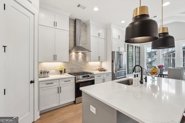 4308 Southside Dr, Acworth, GA 30101 - kitchen with stainless steel appliances, wall chimney range hood, a center island with sink, tasteful backsplash, and light wood-type flooring