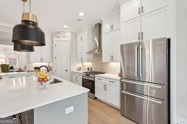 kitchen with a sink, decorative backsplash, appliances with stainless steel finishes, and wall chimney range hood