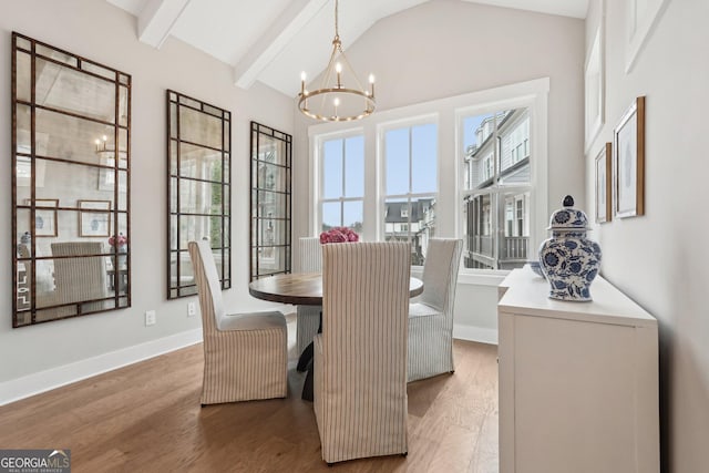 dining room featuring light wood finished floors, a notable chandelier, lofted ceiling with beams, and baseboards