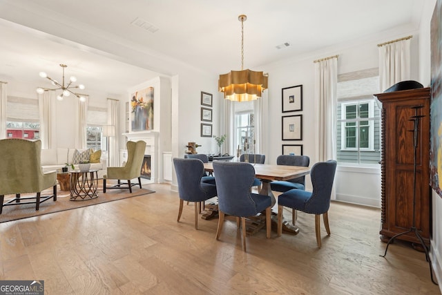 dining area with light wood finished floors, a notable chandelier, a healthy amount of sunlight, and visible vents