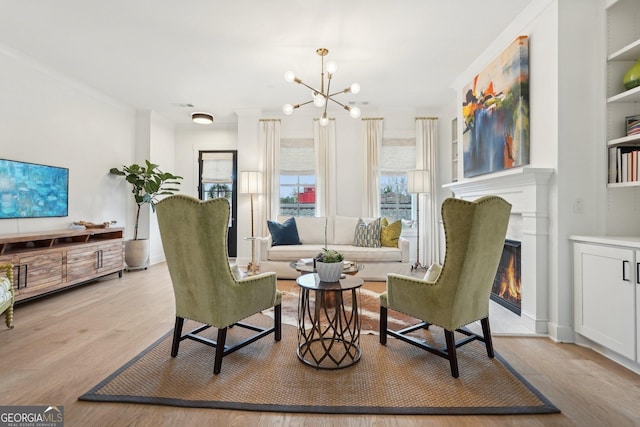living area with a glass covered fireplace, light wood-style floors, and a chandelier