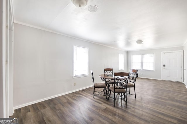 dining space with dark wood-type flooring, crown molding, and baseboards