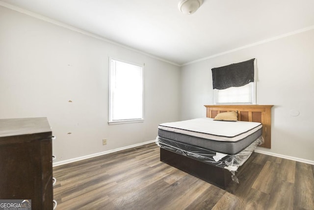 bedroom featuring ornamental molding, baseboards, and wood finished floors