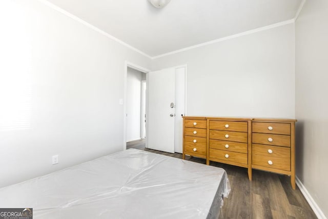 unfurnished bedroom with dark wood-style flooring, crown molding, and baseboards