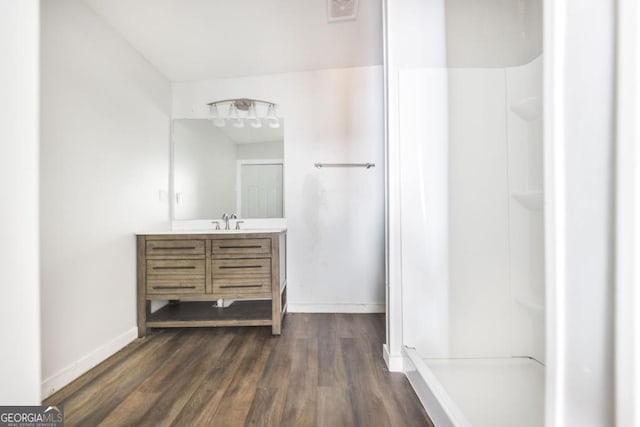 bathroom featuring visible vents, vanity, wood finished floors, baseboards, and walk in shower