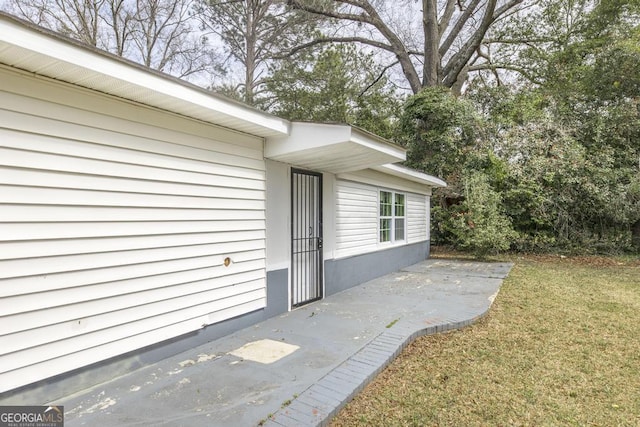 doorway to property with a lawn and a patio