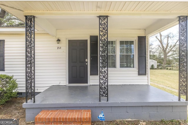 view of exterior entry with crawl space, a porch, and a lawn