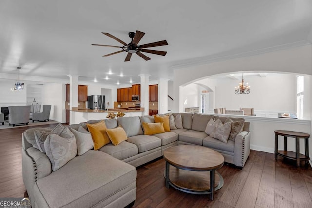 living area with ornamental molding, dark wood-type flooring, and ceiling fan with notable chandelier