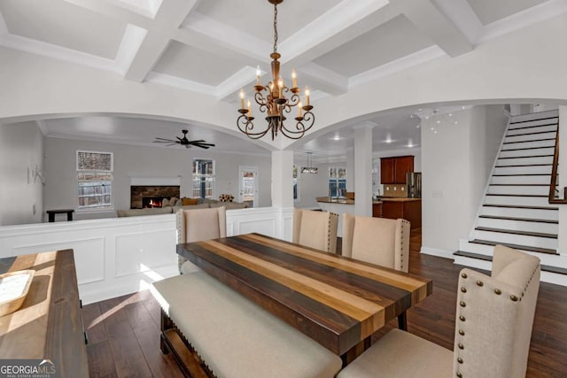 dining area with a fireplace, arched walkways, dark wood finished floors, and a ceiling fan