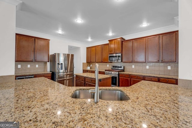 kitchen with light stone counters, stainless steel appliances, a sink, decorative backsplash, and crown molding