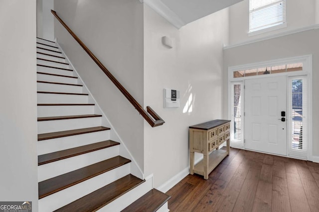 foyer entrance with a high ceiling, stairway, hardwood / wood-style flooring, and baseboards