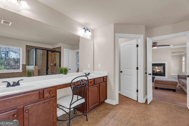 ensuite bathroom with a stall shower, visible vents, a glass covered fireplace, tile patterned flooring, and a sink