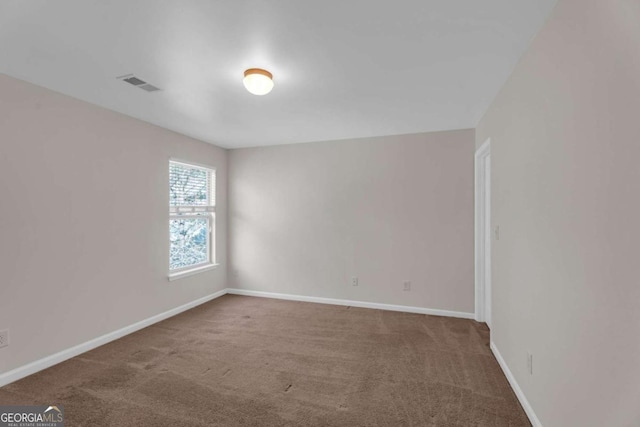 spare room with carpet, visible vents, and baseboards