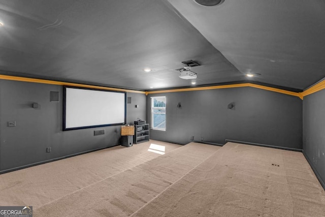 carpeted cinema room with lofted ceiling, baseboards, and crown molding