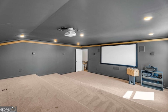 carpeted cinema with vaulted ceiling, visible vents, and crown molding