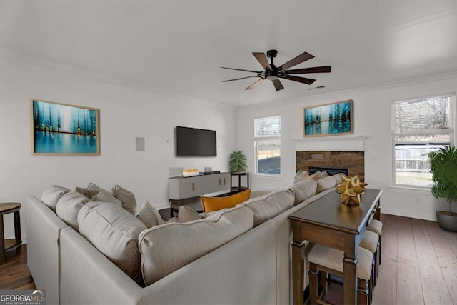 living room with ceiling fan, ornamental molding, a fireplace, and hardwood / wood-style flooring