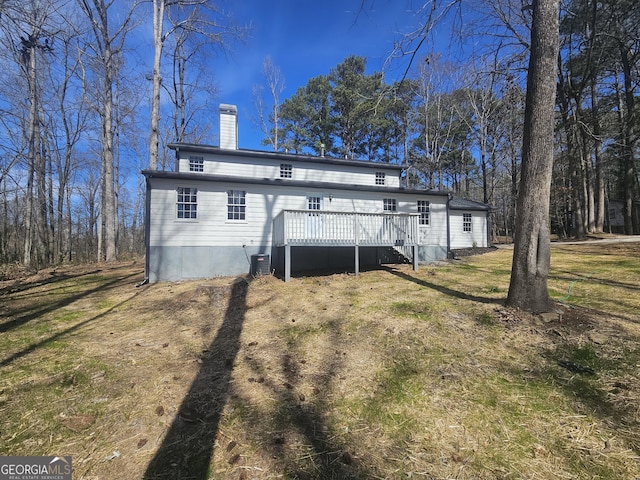 back of property featuring a deck, cooling unit, a yard, and a chimney