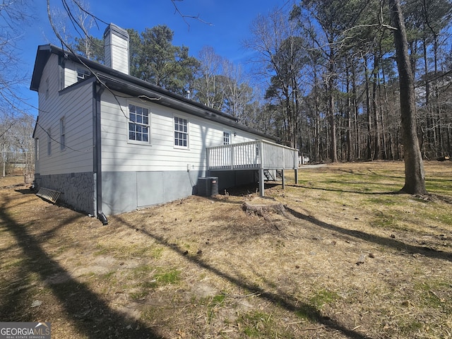 view of property exterior with a deck, a chimney, and central air condition unit