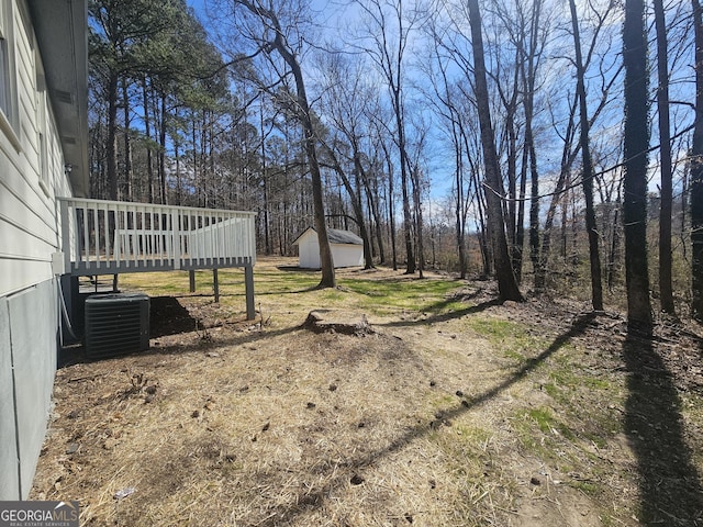 view of yard featuring a storage unit, central AC unit, a deck, and an outdoor structure