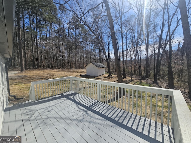 wooden terrace with a storage shed, an outbuilding, and a view of trees