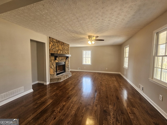 unfurnished living room with dark wood-style flooring, a fireplace, visible vents, and baseboards