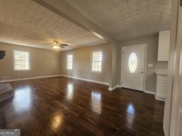 foyer entrance with baseboards, visible vents, dark wood finished floors, a ceiling fan, and a textured ceiling