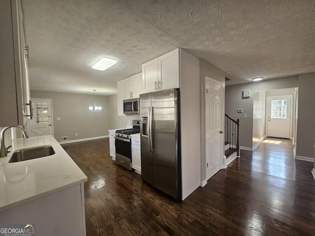 kitchen with stainless steel appliances, a sink, visible vents, white cabinets, and dark wood-style floors