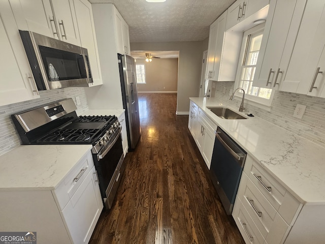 kitchen featuring a textured ceiling, dark wood-type flooring, a sink, white cabinets, and appliances with stainless steel finishes