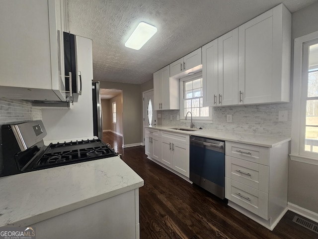 kitchen with dark wood-style flooring, stainless steel appliances, tasteful backsplash, visible vents, and a sink