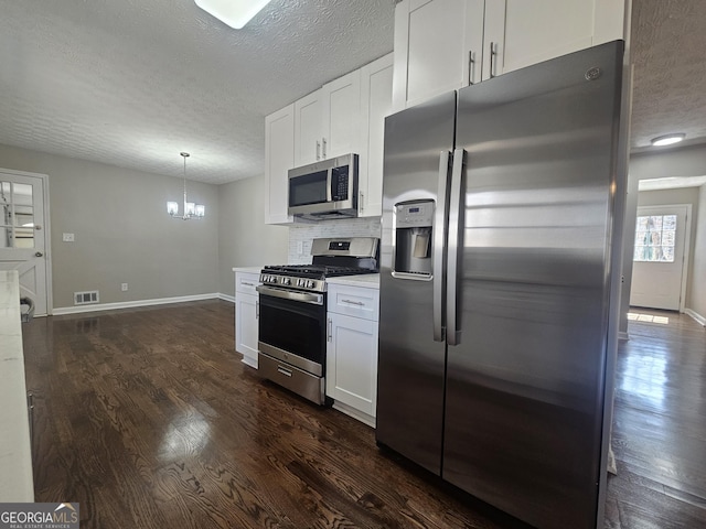 kitchen with a textured ceiling, visible vents, stainless steel appliances, and dark wood-style flooring