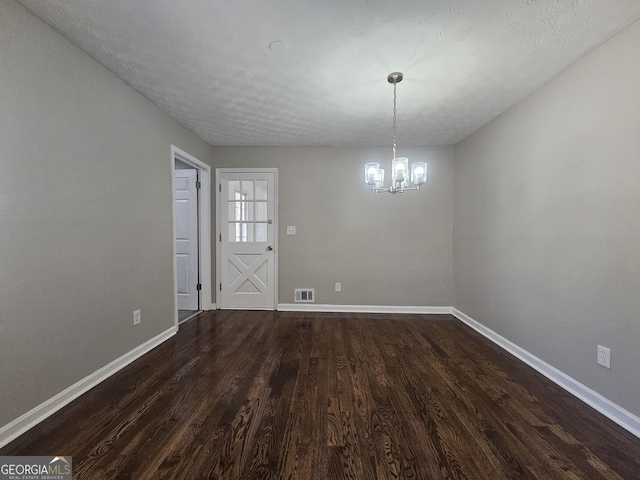 unfurnished dining area featuring a chandelier, dark wood-style flooring, visible vents, and baseboards