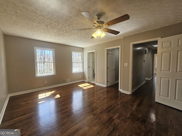 empty room featuring baseboards, a textured ceiling, visible vents, and dark wood-style flooring