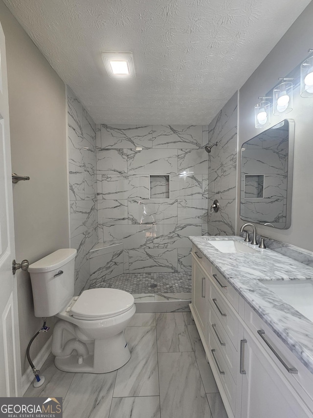 full bath featuring marble finish floor, a marble finish shower, toilet, a sink, and a textured ceiling