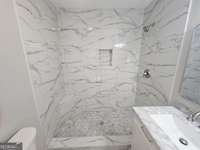 bathroom featuring tiled shower, vanity, and toilet