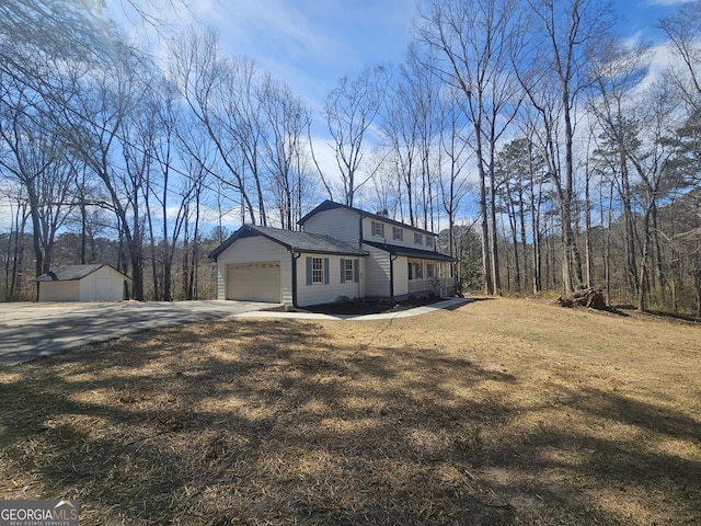 view of side of home with a garage, a chimney, a lawn, and concrete driveway