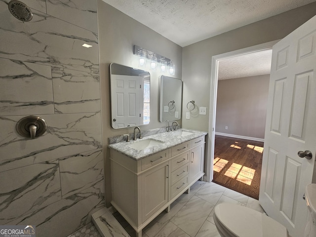 full bathroom featuring marble finish floor, a textured ceiling, and a sink