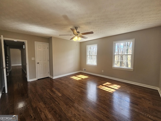 spare room featuring ceiling fan, a textured ceiling, baseboards, and dark wood-style flooring