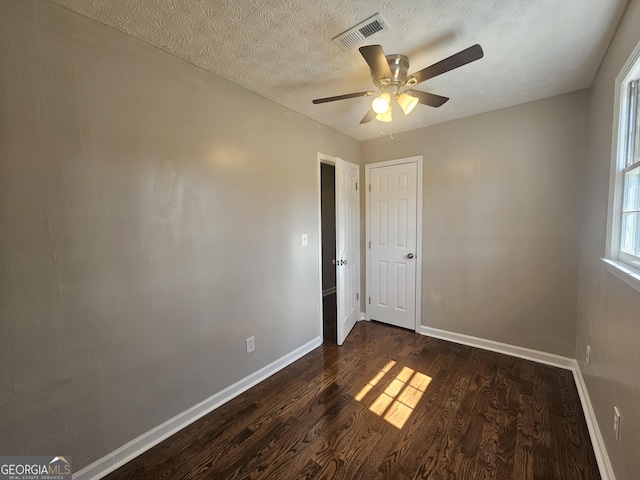 unfurnished bedroom featuring baseboards, visible vents, dark wood finished floors, and a textured ceiling