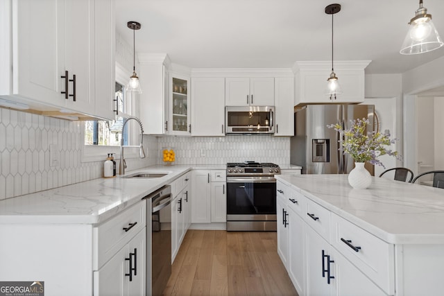 kitchen featuring light wood-type flooring, a sink, tasteful backsplash, white cabinetry, and appliances with stainless steel finishes